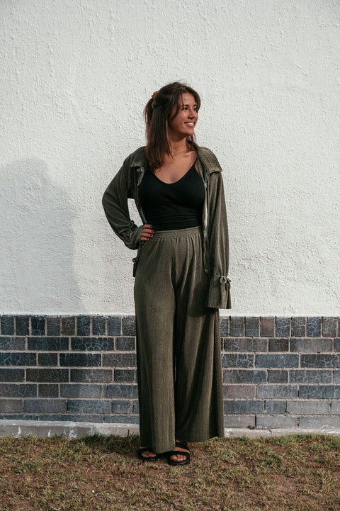 Woman with brown hair wearing the long sleeve plisse top opened with the matching olive plisse pants.