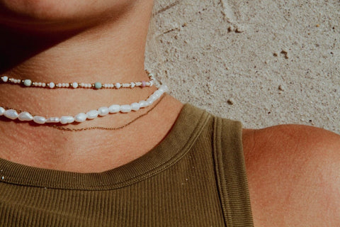 freshwater pearl necklace worn by a woman with a dark top.