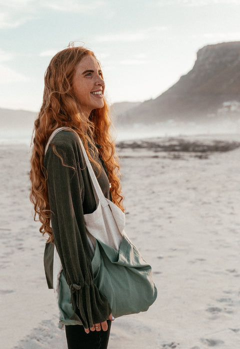 A young woman wearing the olive long sleeve plisse top at the beach in Muizenberg.