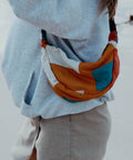 A woman wearing Not I But We's patchwork moonbag at the beach.