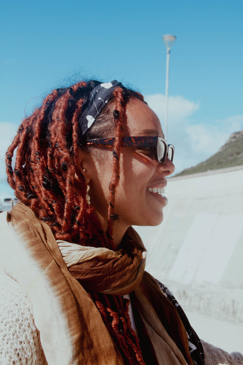 A woman smiling while wearing Not I But We's headband