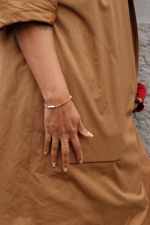 Welcome Bracelet worn by a woman in a brown jacket.